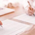 a left white hand holding a silver pen to show how handwritten-appearing signatures can enhance direct mail marketing