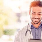 Physician smiles while holding tablet looking for healthcare thought leaders to follow on social media