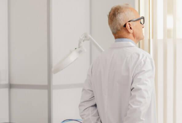 Physician looks out office window preparing to answer patient questions about what is a tripledemic