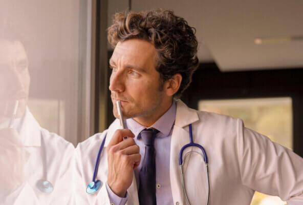 Doctor looks through window pondering solutions to physician burnout