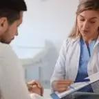 A healthcare professional discussing a chart with a patient in a clinical setting.