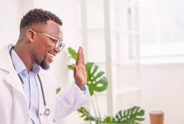 Smiling physician using telehealth software with patient