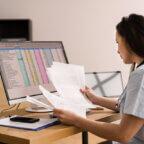 Medical billing professional looks at papers and spreadsheets reflective of Cigna downcoding E/M codes