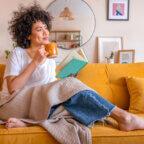 Biller sits on couch at home drinking coffee and reading medical billing books
