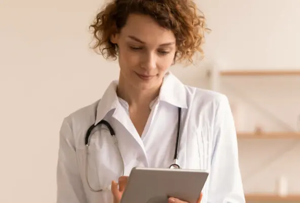 This is an image of a doctor reading information on a tablet screen.