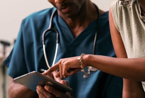 image of patient pointing to tablet screen next to doctor