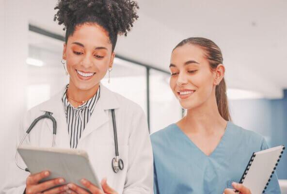 Female physician looking at digital tablet with medical practice staff member.