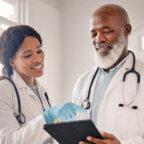 Physicians discuss their medical practice marketing budget while looking at tablet