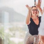 Medical billers exchange a high-five while engaging in networking for medical billing companies