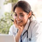 Physician reads April 2025 revenue cycle management healthcare news on laptop