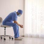 Physician sits near window demonstrating emergency medicine burnout